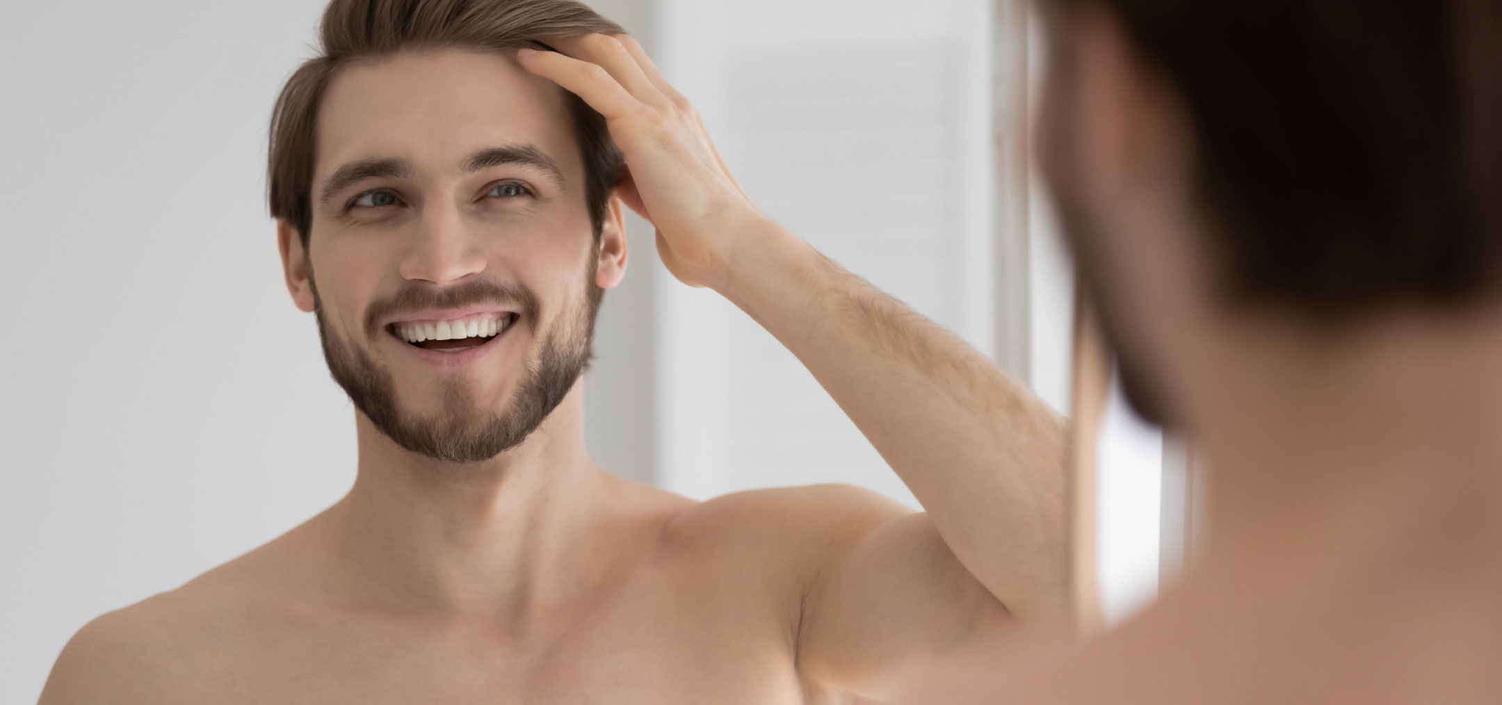 hair transplantation model smiling while combing hair with hand